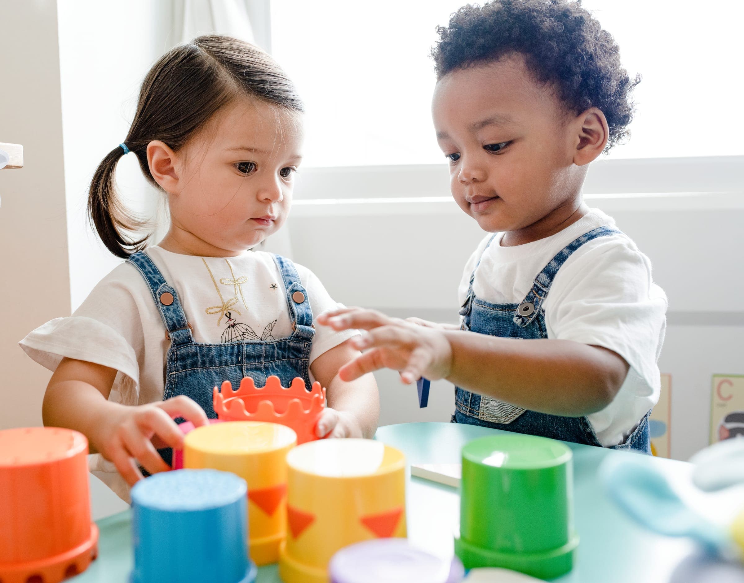 Twee peuters spelen samen met gekleurde stapelbekers